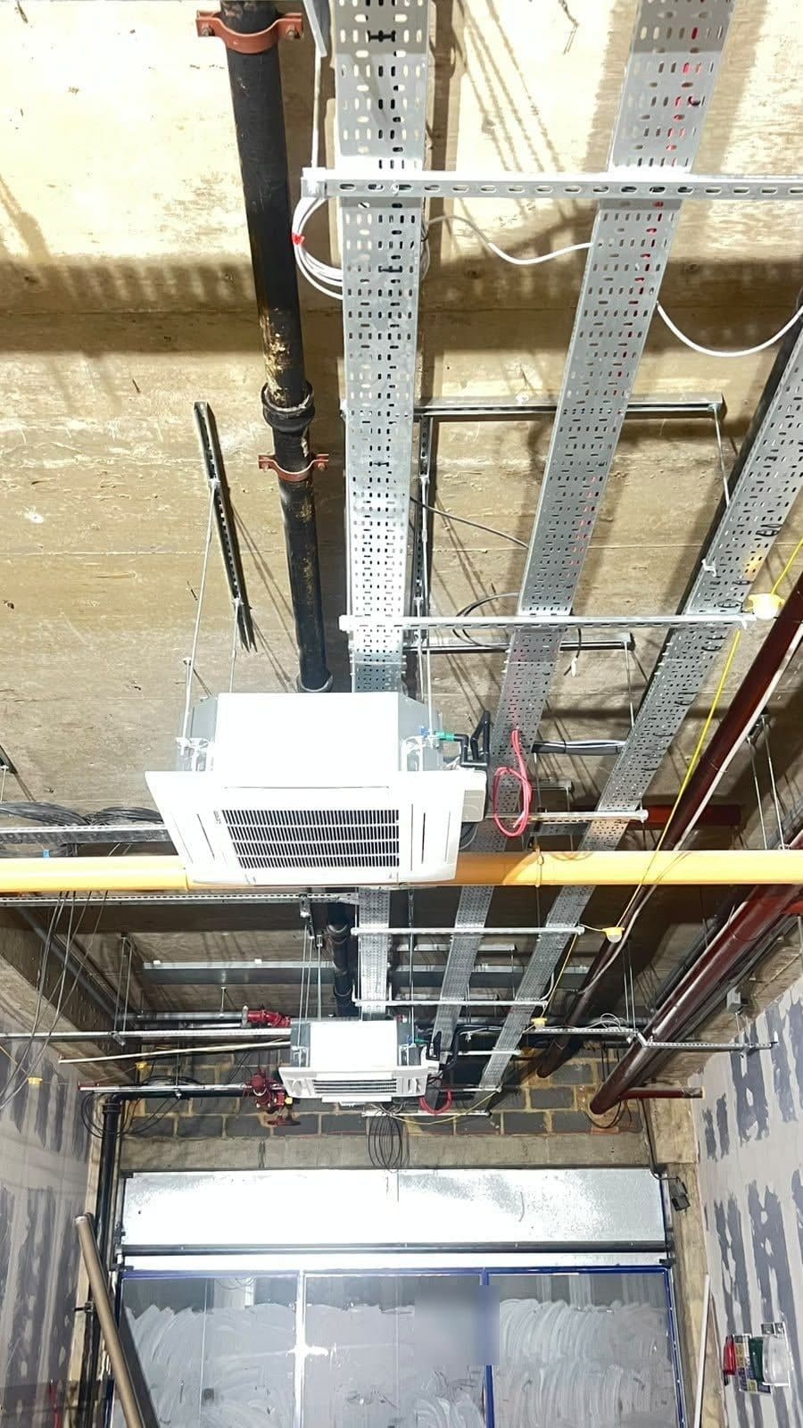 Exposed ceiling in a shop unit with cable trays, pipework and ceiling-mounted air conditioning units