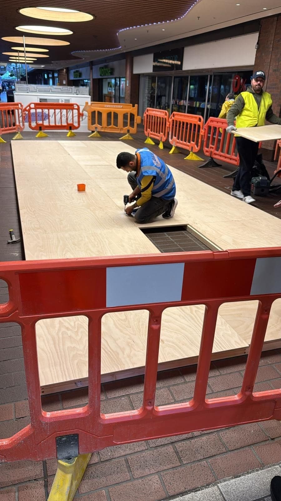 Floor boarding going down for the Freshpoint island unit, with a fitter working inside the barriers