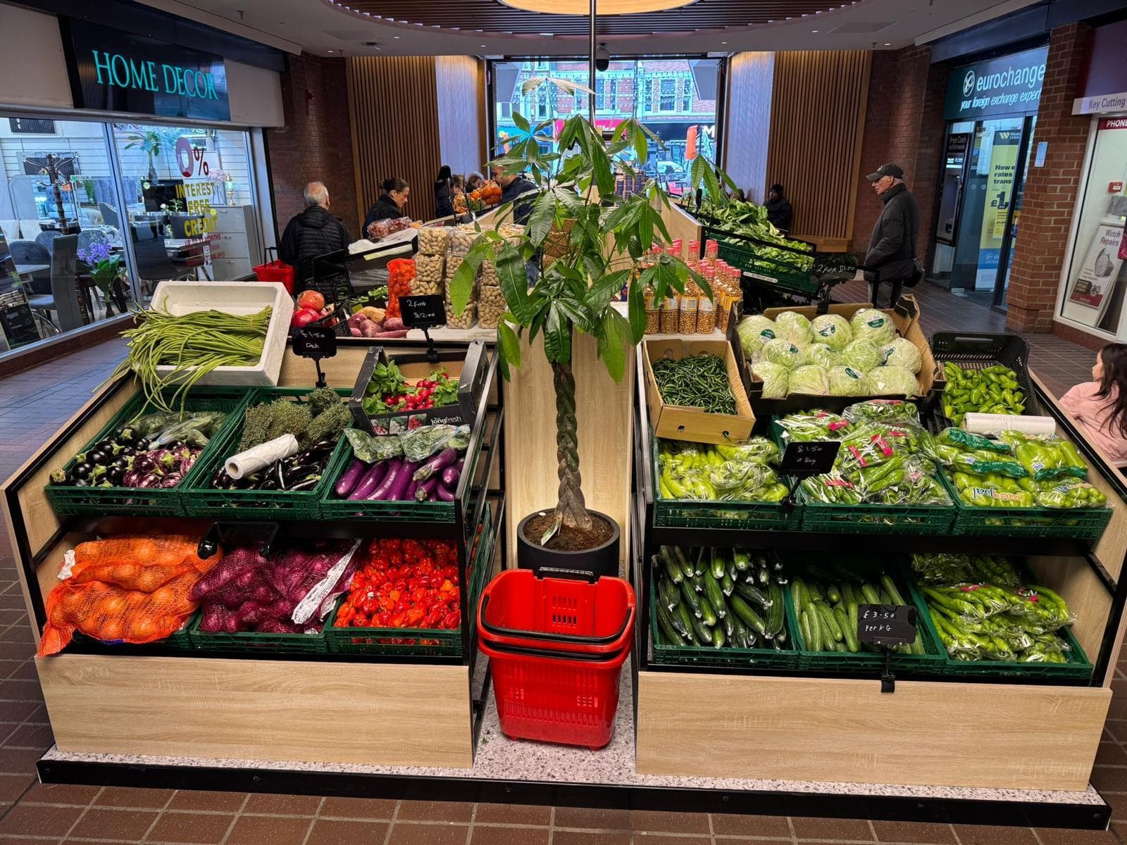 Freshpoint fruit and veg island unit in a shopping centre, with produce displayed in crates on wooden shelving