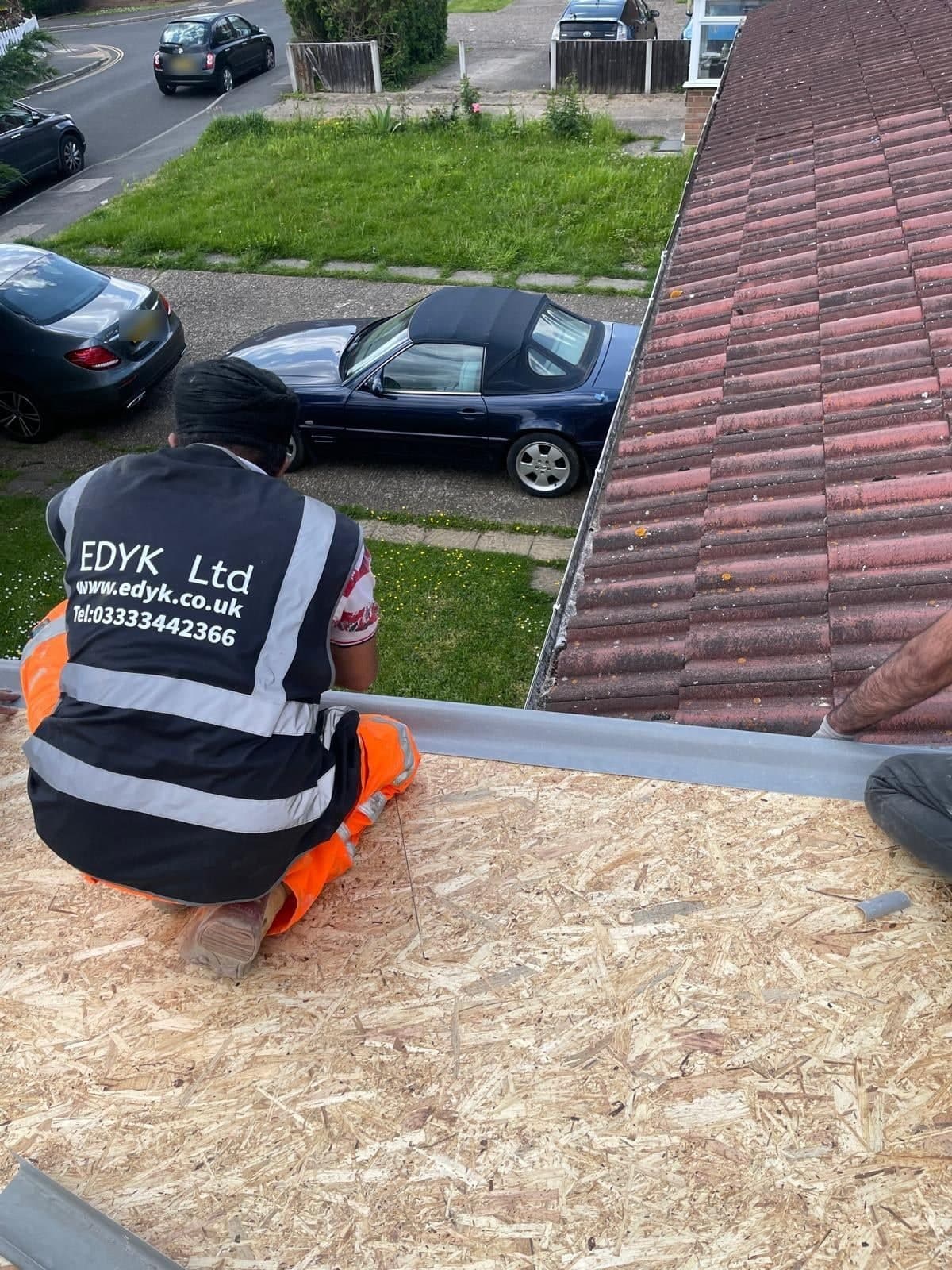 EDYK team member working on the new flat roof deck of the extension, beside the existing tiled roof