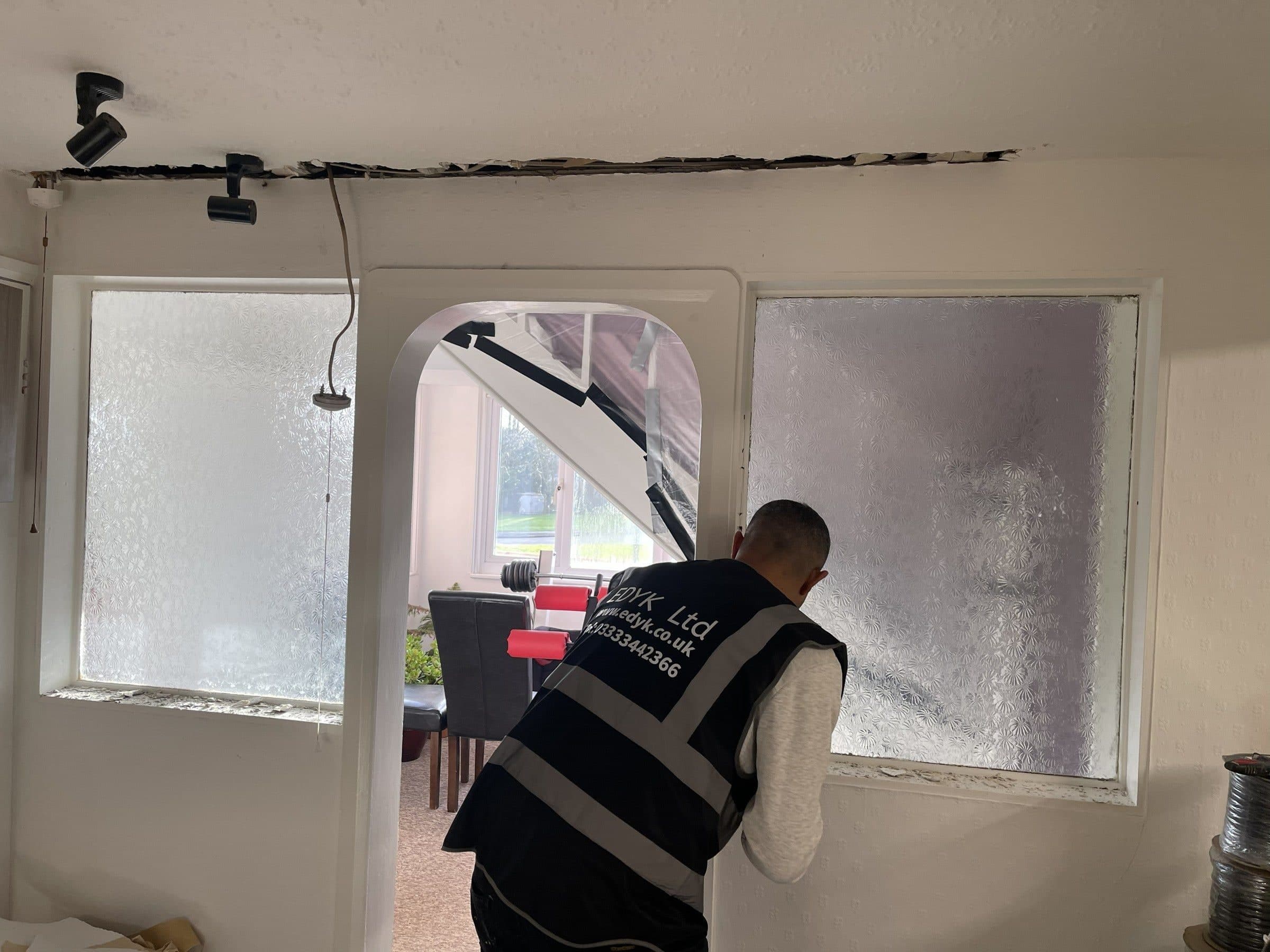 EDYK team member working at a frosted-glass partition and arched opening, with the ceiling opened up above
