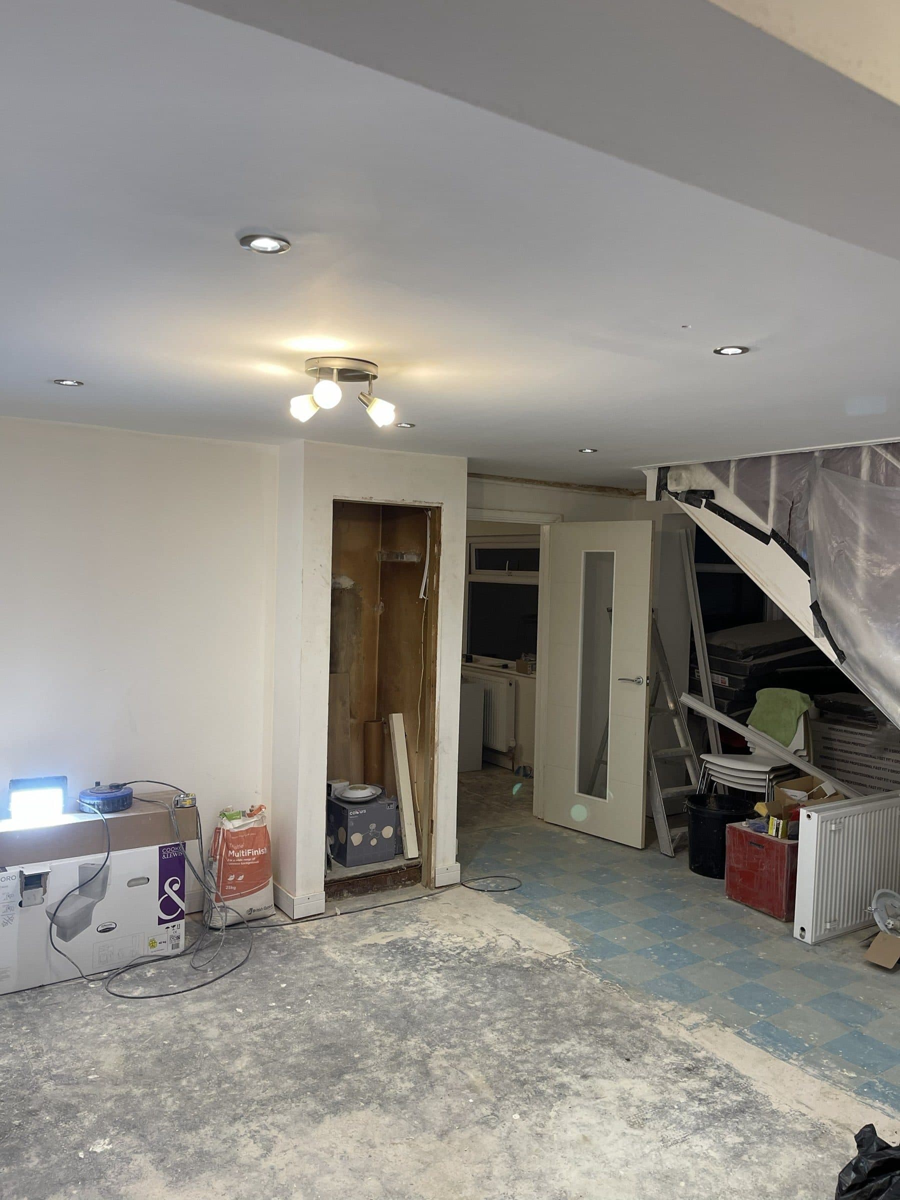 Opened-up room in a house renovation with plastered walls and ceiling, new internal doors and the floor not yet finished