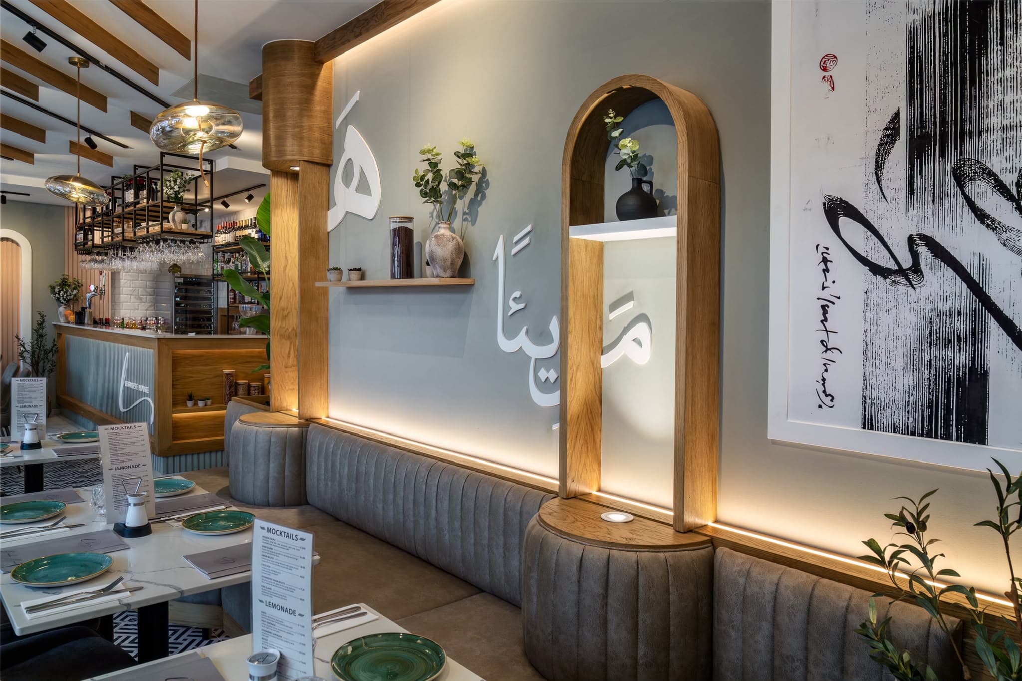 Lebanese House banquette seating beneath a wall with Arabic lettering and an oak arched niche