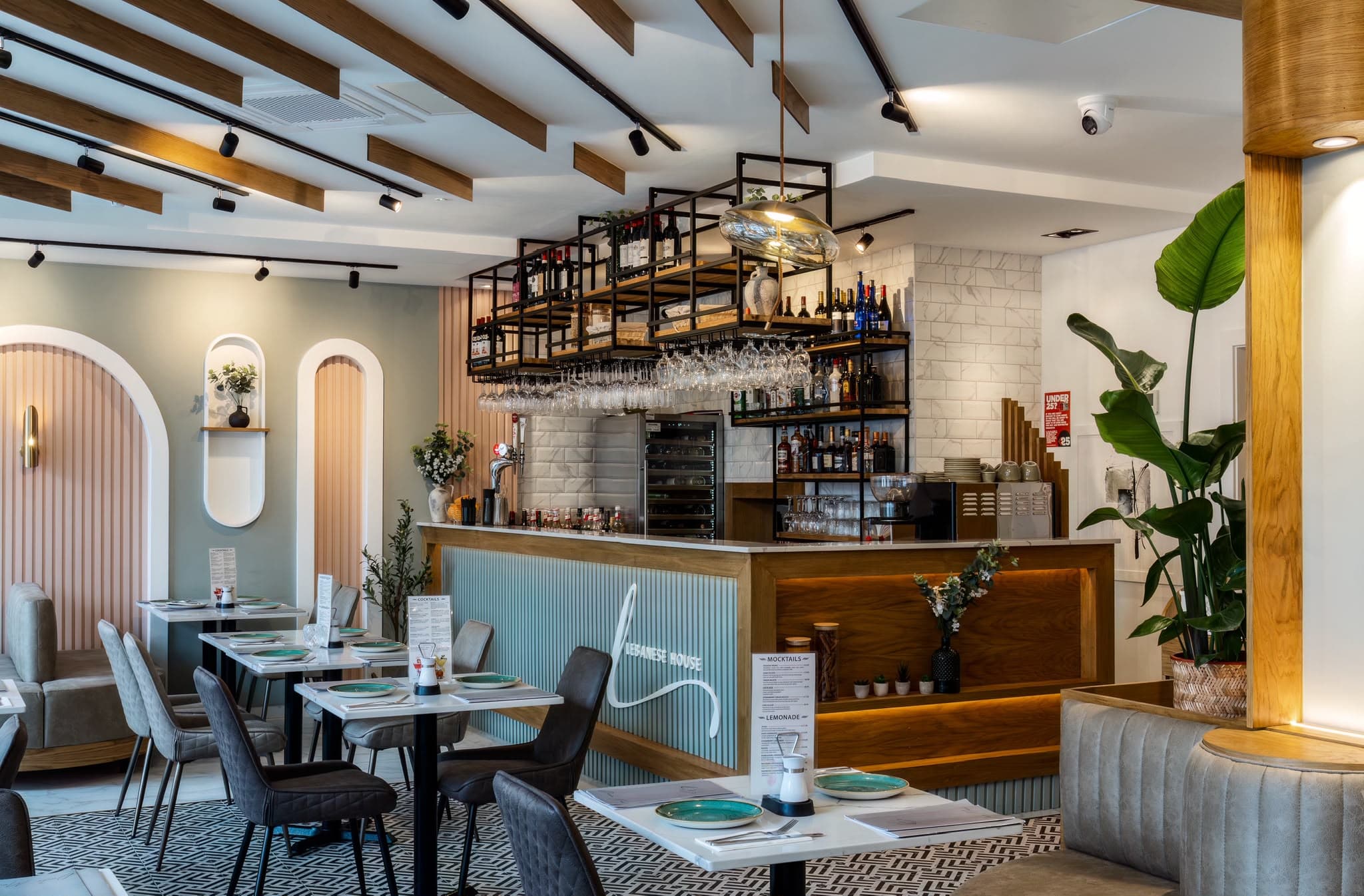 Lebanese House bar with black steel shelving above a fluted pale blue front, and arched alcoves behind