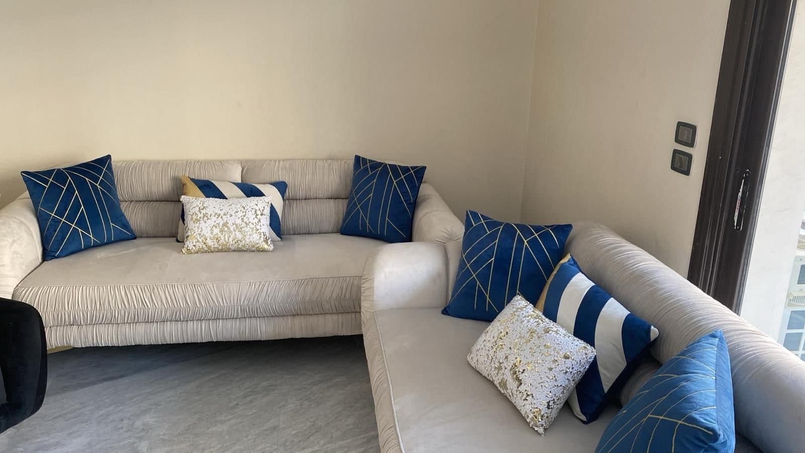 Apartment living room with cream corner sofas and blue and gold cushions